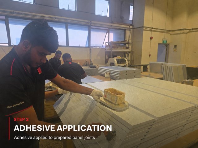 Step 2, adhesive application: a fabricator drawing an adhesive block along the grooved edge of a stacked PIR panel.