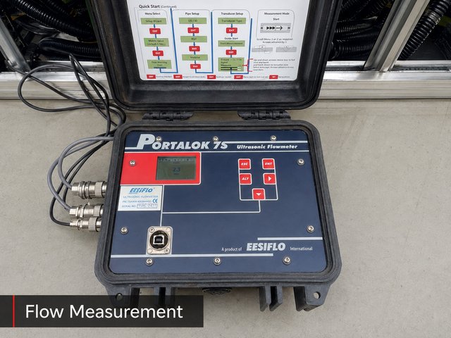 A Portalok 7S ultrasonic flowmeter in its portable case, used for non-intrusive refrigerant flow measurement.